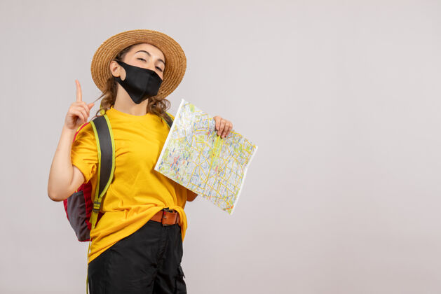 旅行者正面图年轻的旅行者背着背包举着地图指向上人肖像旅游