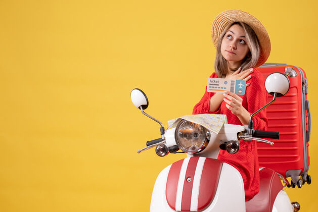 旅游正面图：穿着红衣服的年轻女士拿着车票坐在轻便摩托车上仰望冒险轻便摩托车车辆