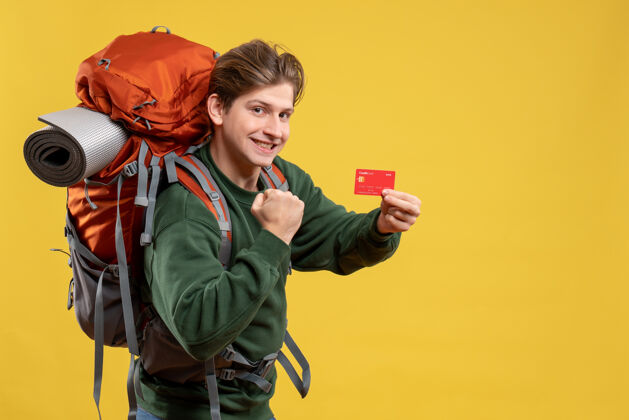 成人正面图年轻男子手持红色银行卡准备远足旅游度假旅游