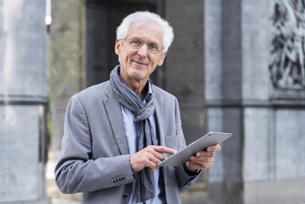 外面时尚的老男人在城市里使用平板电脑老年人老碑