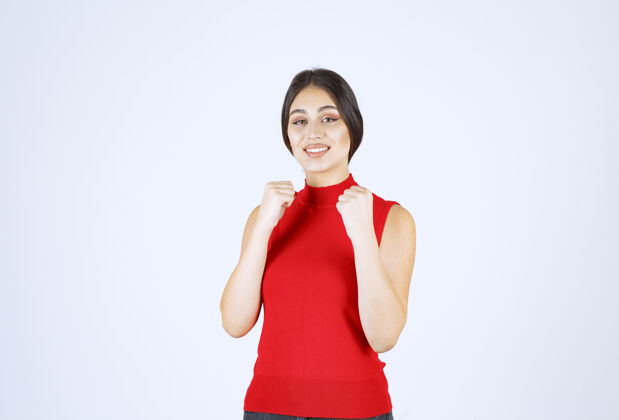 装备穿红衬衫的女孩展示她的手臂肌肉和拳头工人动力强壮