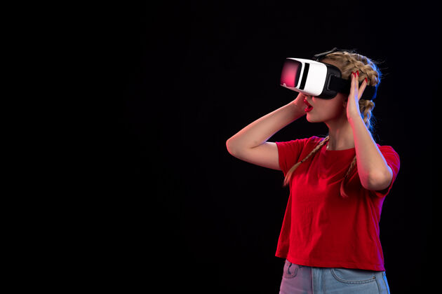 游戏兴奋的年轻女性在黑色表面上玩虚拟现实的前视图虚拟现实广播超声波
