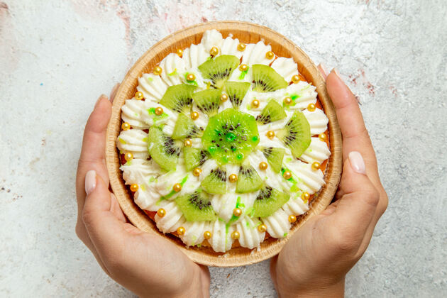 视图俯瞰美味的猕猴桃甜点与白色奶油和切片猕猴桃上的白色背景甜点水果糖果奶油蛋糕糖果切片蛋糕