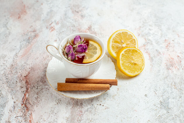 健康前视图一杯茶与肉桂和柠檬片上的淡白色空间一餐柑橘碗