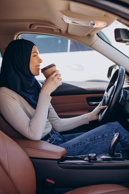 年轻的现代妇女在车里喝咖啡女人喝酒头巾