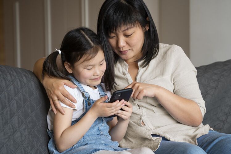 家庭中枪的女人和带电话的女孩生活方式中镜头孩子