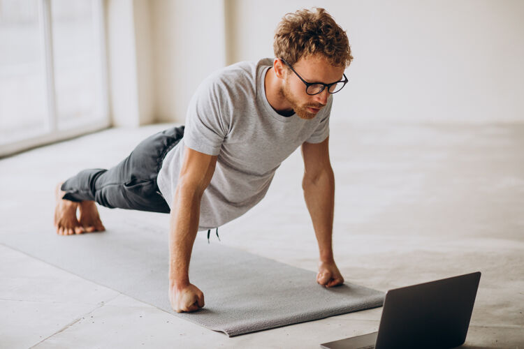 注意力运动的男人看教程和练习瑜伽垫上锻炼柔韧冥想