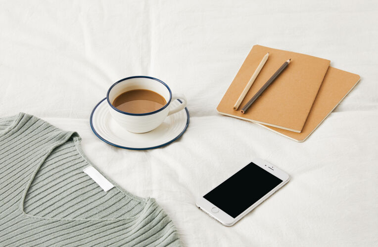 日记一杯咖啡放在床单上的高角度照片 上面有素描本 电话和毛衣床单角度电话