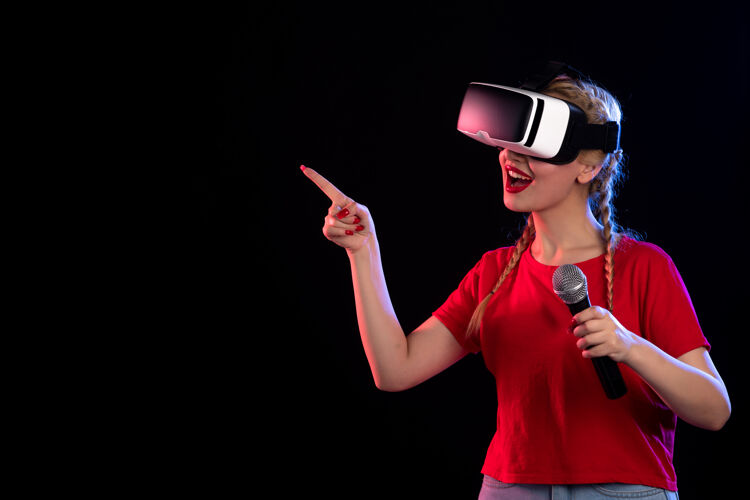 虚拟现实年轻女性在黑暗的墙上玩虚拟现实和用麦克风唱歌的画像麦克风黑色麦克风