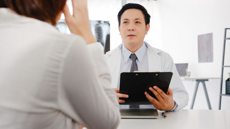 保险严肃的亚洲男医生穿着白色医疗制服 用剪贴板发表精彩的新闻谈话 讨论结果医生药品疾病