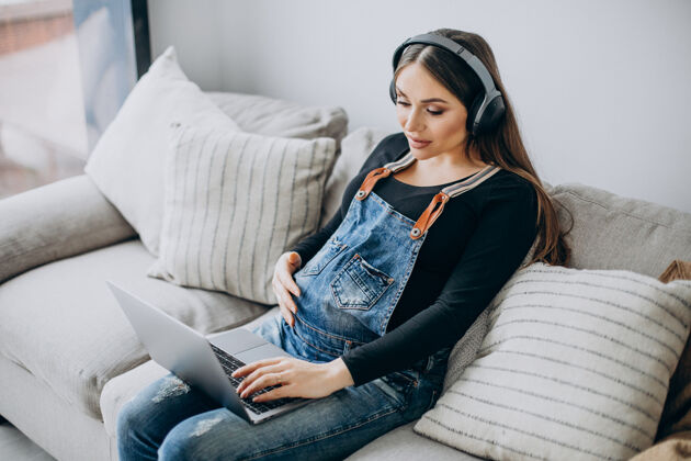 生活孕妇戴着耳机听音乐上网耳机女士笔记本电脑