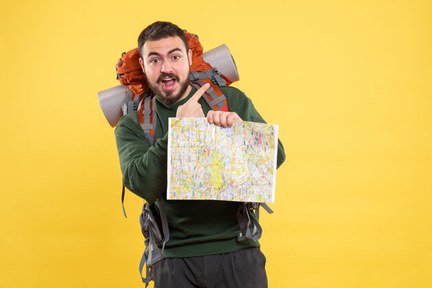 人顶视图年轻微笑旅行的家伙背着背包拿着地图 指着黄色顶人年轻人