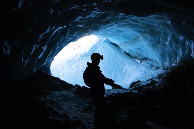 岩石孤独的男人白天在覆盖着雪的笼子里登山松树徒步旅行雪