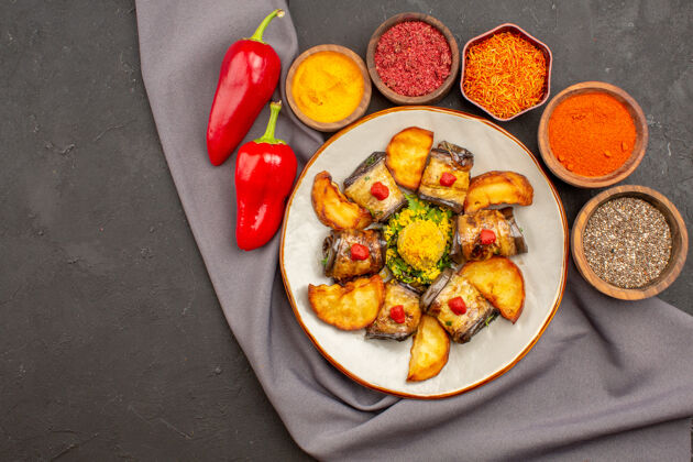 土豆俯瞰美味的茄子卷烹调菜肴与烤土豆和调味料上的深色背景菜烹饪土豆早餐调味品烘焙