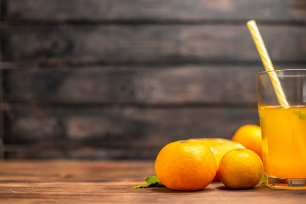水果侧视图新鲜的橙汁在一个玻璃与管薄荷和整个切橙子在一个木桌上柑橘薄荷餐桌