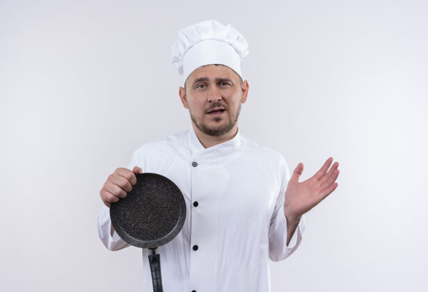 年轻年轻帅气的厨师身着厨师制服 手拿煎锅 空手孤立在白墙上印象烹饪厨师