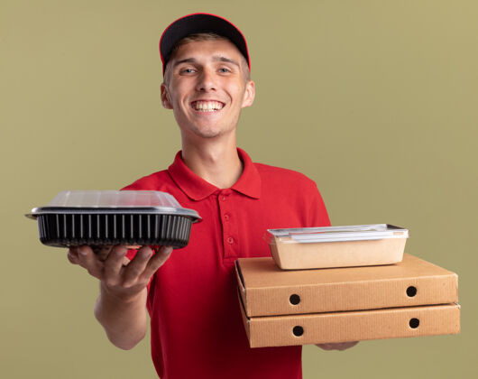 容器微笑的年轻金发送货男孩拿着比萨饼盒上的食品容器和食品包装男孩盒子橄榄