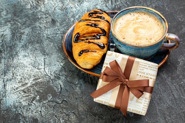 咖啡一杯咖啡的侧视图和新鲜美味的烤面包和礼物在黑暗的表面早餐小吃垃圾