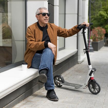 退休坐在户外拿着滑板车的全镜头男人老年人户外城市