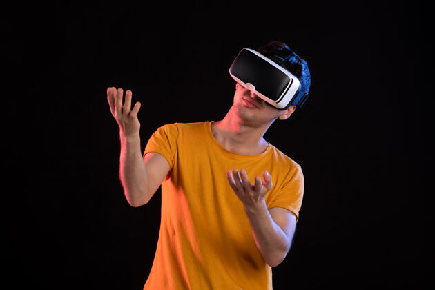 游戏在黑暗的墙壁上玩虚拟现实的年轻男性的正面视图正面现实视觉