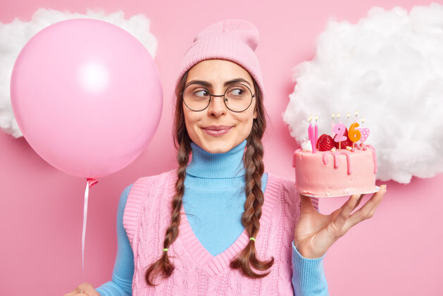 请扎着辫子的女孩看起来很梦幻 戴着圆眼镜 穿着休闲服 手里拿着粉红色的充气气球蛋糕女人站立个人