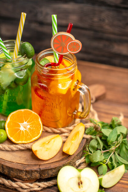 酸橙美味的新鲜果汁和水果在木制托盘上棕色背景的正面视图柠檬柑橘背景