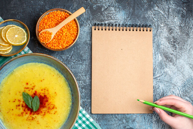 背景上图：手提笔放在螺旋笔记本上 美味的汤配薄荷和胡椒 放在绿色的毛巾上控股碗胡椒