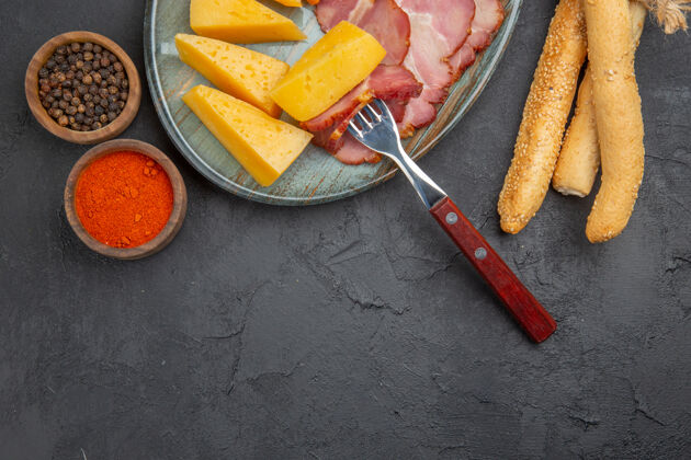 食物半张美味的香肠和奶酪片放在蓝色的盘子里 黑底胡椒午餐背景胡萝卜
