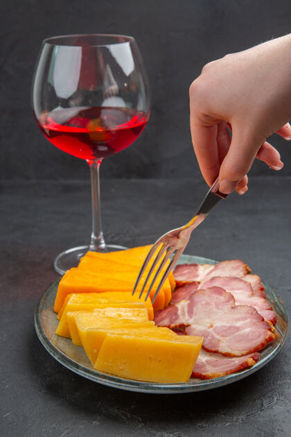 水果垂直视图手拿叉子放在蓝色盘子上 杯子里有美味的小吃和红酒叉子杯子背景