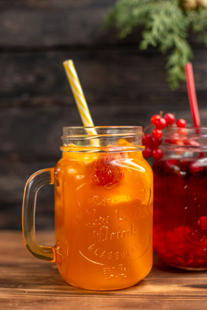 玻璃天然新鲜果汁装在瓶子里 配上管子和水果 背景为棕色木质液体果汁服务