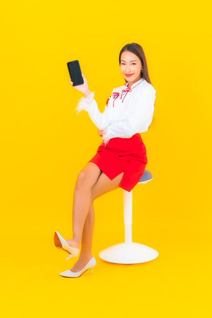 青少年用黄色的智能手机描绘美丽的亚洲年轻女子欢呼休闲年轻