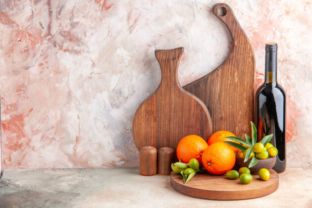 五颜六色各种木制砧板和新鲜柑橘类水果酒瓶的正面图 左侧是五颜六色的表面壁灯柑橘景观