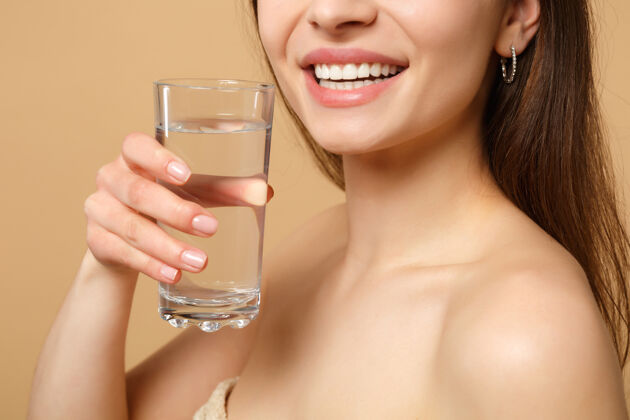 光滑特写黑发半裸完美皮肤的女人裸妆玻璃水隔离米色粉彩墙纯净水疗健康