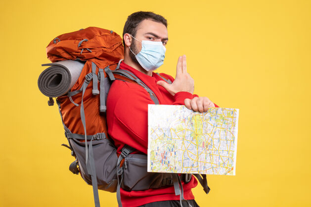 人顶视图年轻的思想旅行者家伙戴着医疗面具与背包举行地图指向上黄色假日购物者医疗