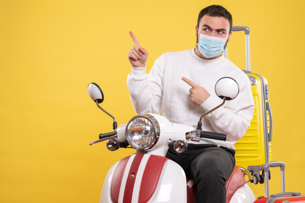 人带着医用面罩的好奇的家伙坐在摩托车上 黄色的手提箱放在黄色的上面成人男运动