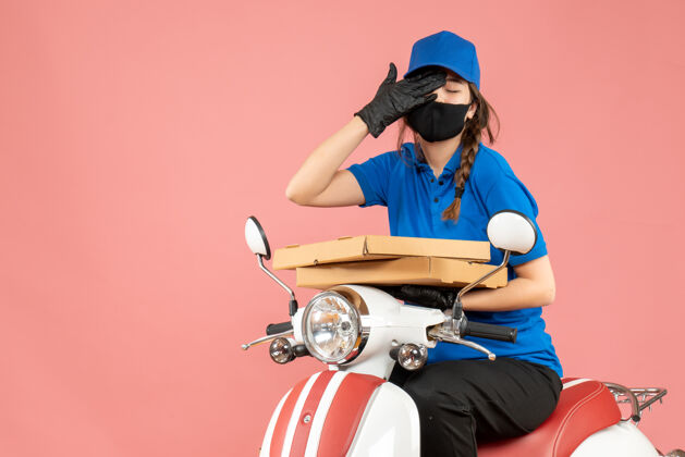 面具俯视图：疲惫的女快递员戴着医用口罩和手套坐在滑板车上 用柔和的桃色传递订单人头盔滑板车