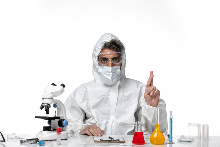 实验室外套穿防护服的男医生 戴着消毒口罩 手指交叉在白色皮肤上大流行面罩十字架