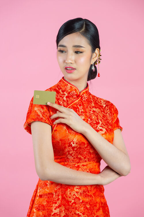 金钱美丽的亚洲女人开心的微笑 在粉色背景上展示中国新年的信用卡购物展示东方