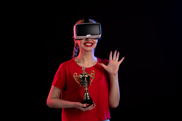 游戏前视图的年轻女性玩虚拟现实与赢家杯在黑暗的地板视觉d科技游戏视觉正面赢家