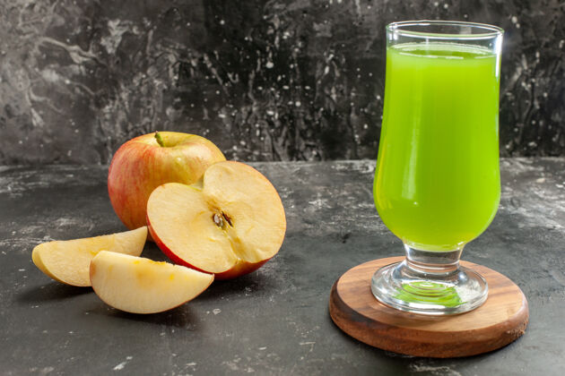 冷的前视图新鲜成熟的苹果与绿色的苹果汁对一个黑暗醇厚的果汁树照片的颜色水果苹果玻璃杯