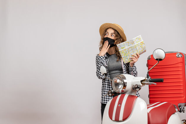 站立一个戴着黑色面具的年轻女孩拿着地图站在红色的轻便摩托车旁边肖像模特成人