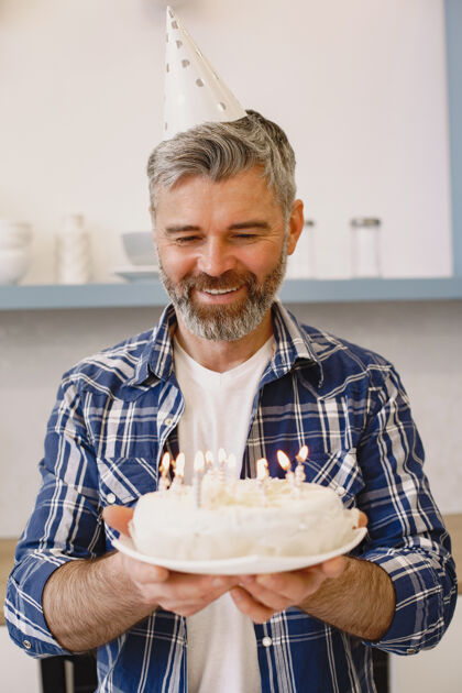 漂亮戴派对帽的男人拿着蛋糕和蜡烛男人穿衬衫帽子礼物礼物
