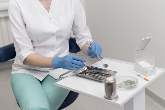 医疗戴着乳胶手套的女正畸医生在操作牙科设备正畸医生妇女牙医