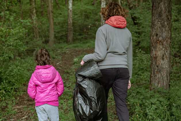 慈善妈妈和女儿用垃圾袋清理环境中的垃圾护理社区保存