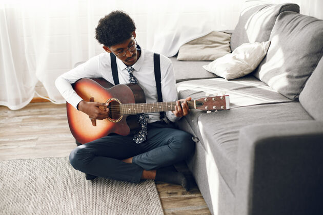 休息Hoobies概念穿着紧身衣的印度年轻人坐在客厅里音乐家在弹吉他歌曲音乐无忧无虑
