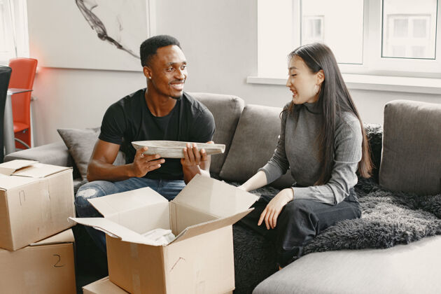 盒子年轻夫妇的肖像与纸板箱在新家 搬家的概念房子搬迁租赁