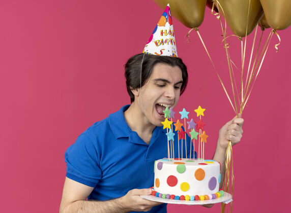 生日高加索帅哥戴着生日帽 手里拿着氦气球 假装咬生日蛋糕蛋糕氦男人