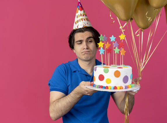 氦戴着生日帽的白人帅哥拿着氦气球和生日蛋糕粉色男人拿着