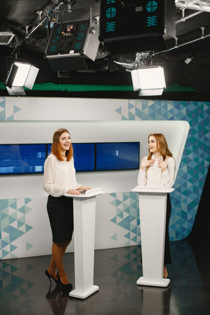 媒体电视游戏节目有两名参与者站在讲坛上兴奋的妇女在电视演播室 拍摄电视节目采访20多岁麦克风