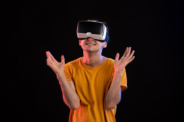 视频戴着虚拟现实耳机的年轻人在黑暗的墙上的画像成人虚拟现实男人
